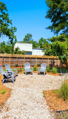 Adirondack chairs in a landscaped backyard seating area